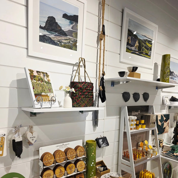 A retail display featuring white Plankwall slatwall panels with white PVC J inserts in a wide 150mm pitch on walls with New Zealand tourist art objects displayed on shelves for sale