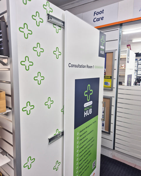 Sliding door with green cross patterns and a Health Hub sign in a medical setting