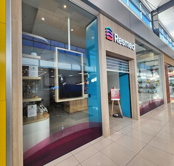 Resmed store entrance with glass door and visible interior. Panel work on shop front finished with Stickman MC18 aluminium corners