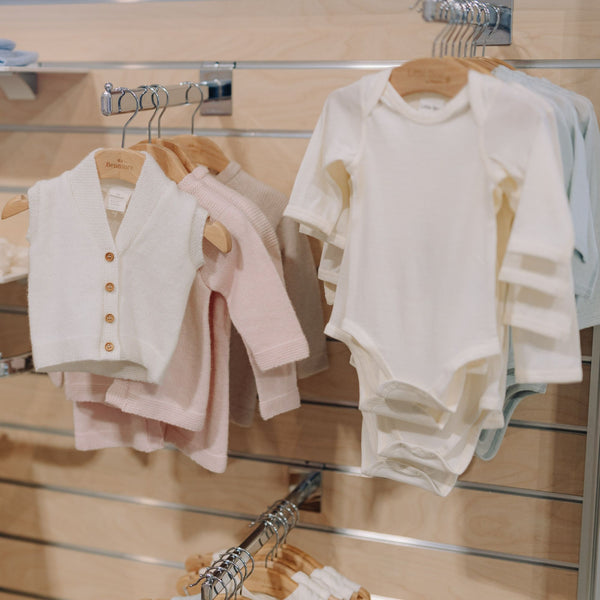 Baby clothes hanging on slatwall straight arm display brackets in a store setting