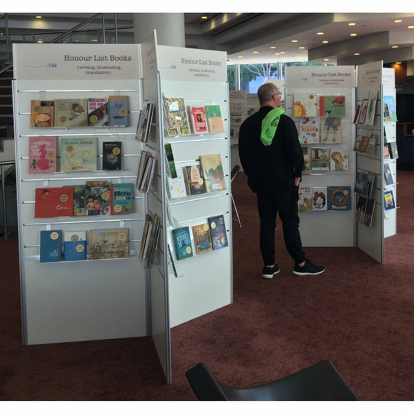 Person browsing books at a book fair with Plankwall 3 way radial display stands on either side.