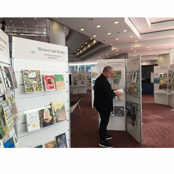 Man browsing books in an exhibition with Plankwall bookshelves and slatwall display units.