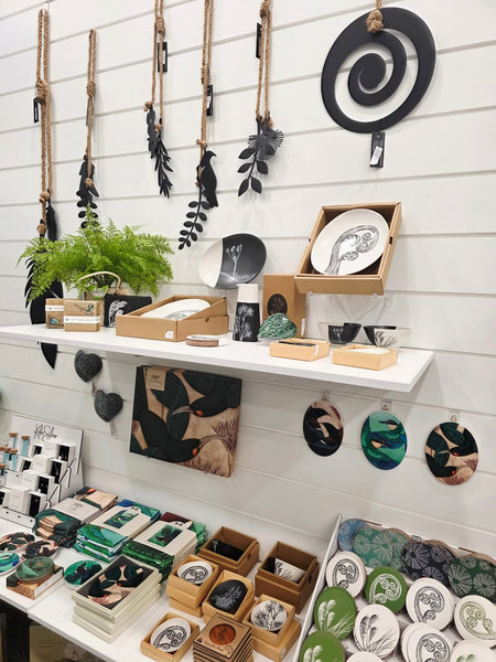 Display of decorative items including ceramic plates, stones, and wall art on white slatwall panels.