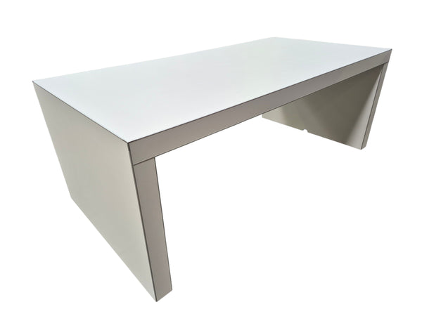 A modern minimalist white desk with a thick rectangular top and sculptural angled legs, shown on a plain white background.