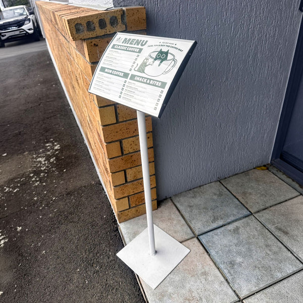 Menu in radius postaframe floor stand with a menu on a sidewalk next to a building