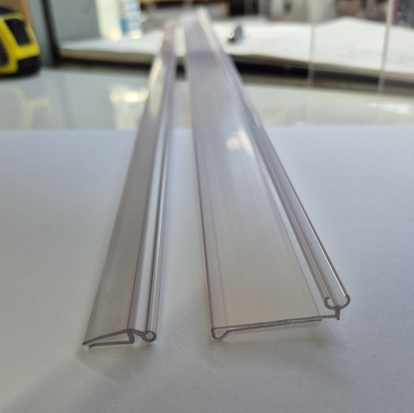 Two clear plastic profiles on a white surface with a blurred background