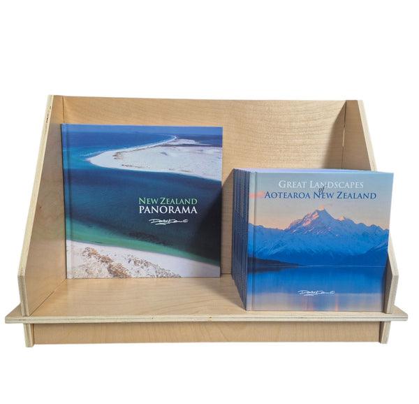 Two books titled 'New Zealand Panorama' and 'Great Landscapes Aotearoa New Zealand' on a custom design wooden display stand.