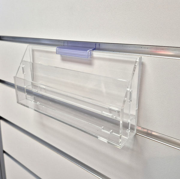 Clear plastic 2 slotted slatwall form holder with a clear clip on a white background