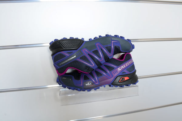 close-up retail photo of a running shoe on a clear polycarbonate shoe shelf