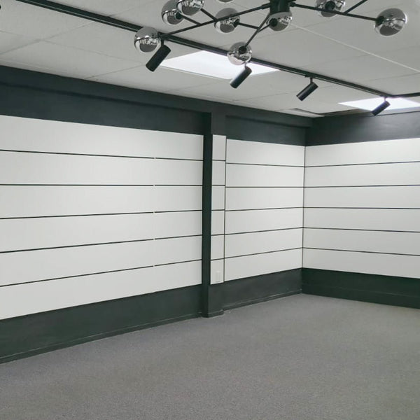 custom made slatwall panel modern office space with white walls, black trim, and ceiling lights.