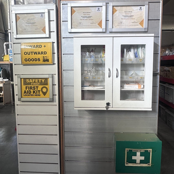Storage display cabinet with shelves and a green first aid box in a warehouse setting