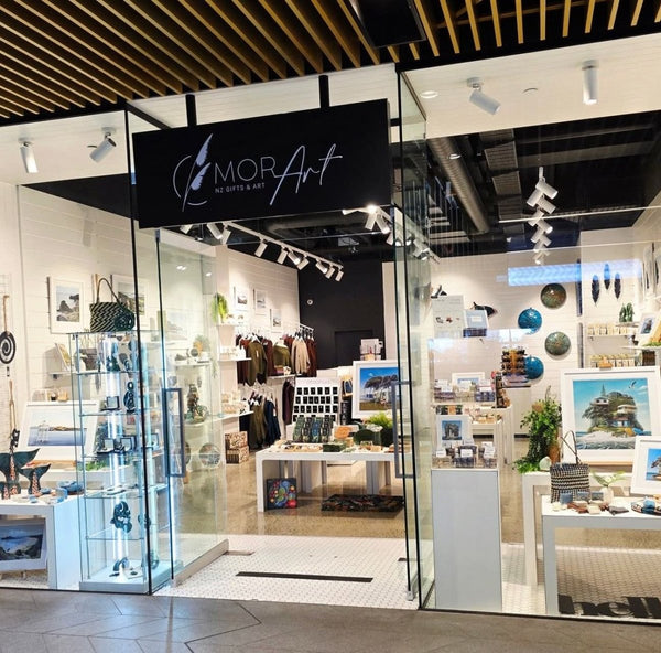 Storefront of Mor Art with various art pieces displayed inside on Plankwall nesting tables, plinths and white slatwall panels.