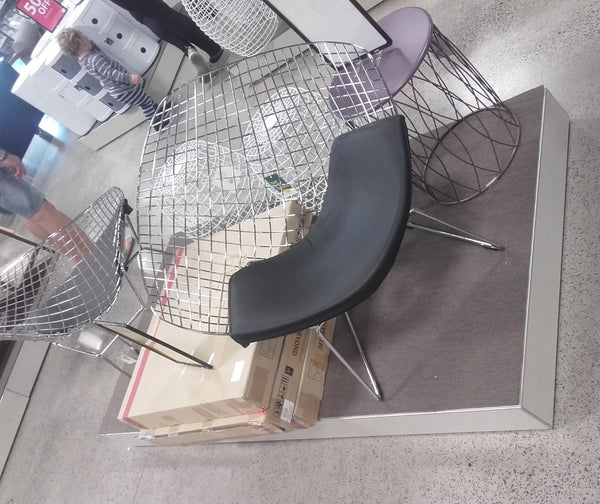 sideways shot of chairs merchandised in a furniture retail store on a low white display plinth covered with grey carpet.