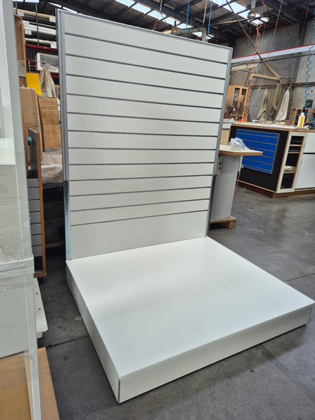 Plankwall free standing slatwall display stand with an extra large bespoke 1000D base shown  in side view in a factory setting