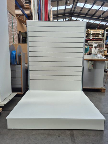 Plankwall free standing slatwall display stand with an extra large bespoke 1000D base shown  in front view in a factory setting