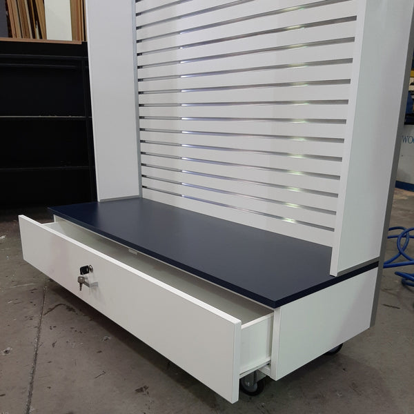 Close up of a lockable drawer in the base of a Plankwall slatwall panel display stand with side walls in a factory setting