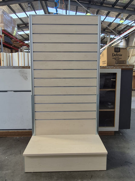 freestanding light weight slatwall display panel in a light wood finish in a factory setting