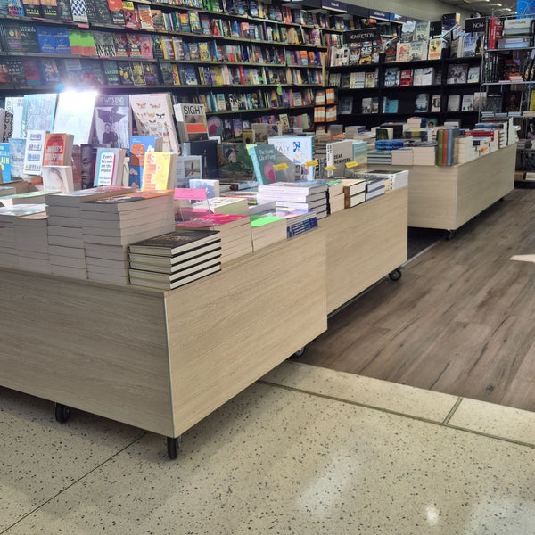 Bookstore interior with shelves and floor display plinths displaying books.