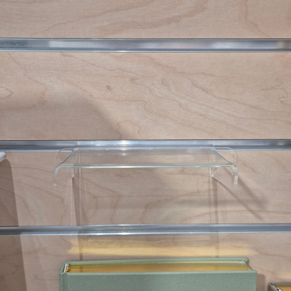 Plankwall clear acrylic display shelf mounted on slatwall, providing a clean, low-profile retail display solution.