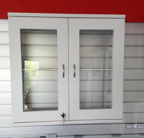 White two door cabinet with glass doors against a red wall