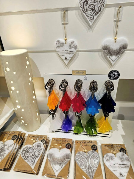 Colorful keychains displayed on a stand with packaging and a decorative heart in the background with keyhole clip on slatwall 
