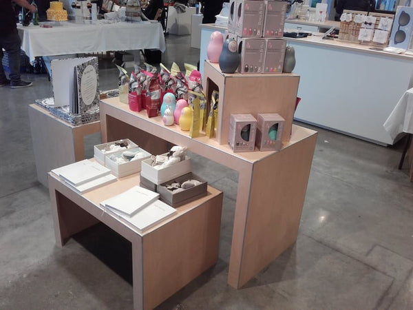 Display of retail products merchandised on a set of three retail display tables in a baby store