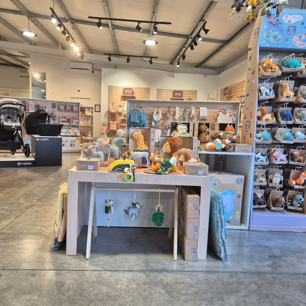 Walnut wood finish retail display table merchandised with baby toys in a retail store.