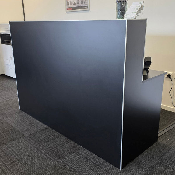 Black Plankwall reception desk in an office setting with a white wall and carpeted floor.