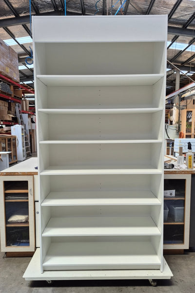 Large white display cabinet with shelves in a warehouse setting