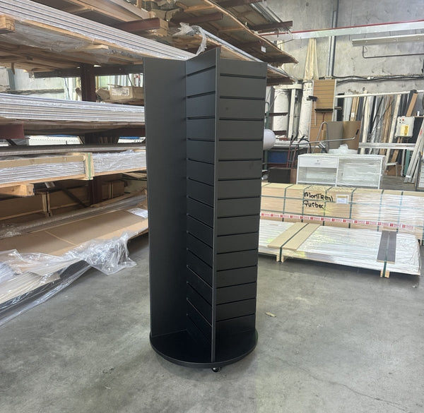 Black on black. Four sided retail display stand powder coated in black with black inserts on a rotating plinth stand waiting for pickup at the factory in East Tamaki
