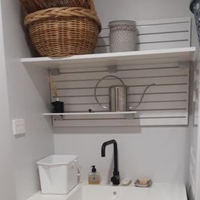 Plankwall All Ali white aluminium slatwall used as wall mounted storage in laundry