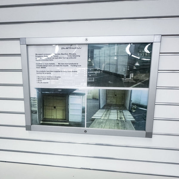 Photo of a horizontal Plankwall lockable snap frame for signs and posters mounted in a slatwall panel 