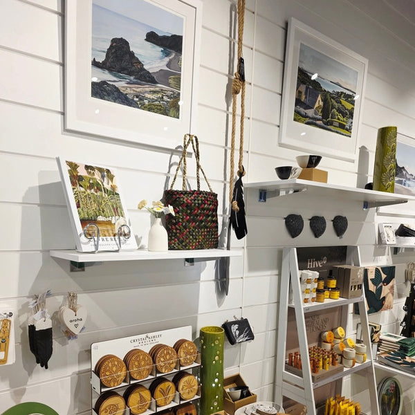 A retail display featuring white Plankwall slatwall panels with white PVC J inserts in a wide 150mm pitch on walls with New Zealand tourist art objects displayed on shelves for sale