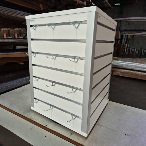 white rotating counter top retail display stand with prongs in a factory setting