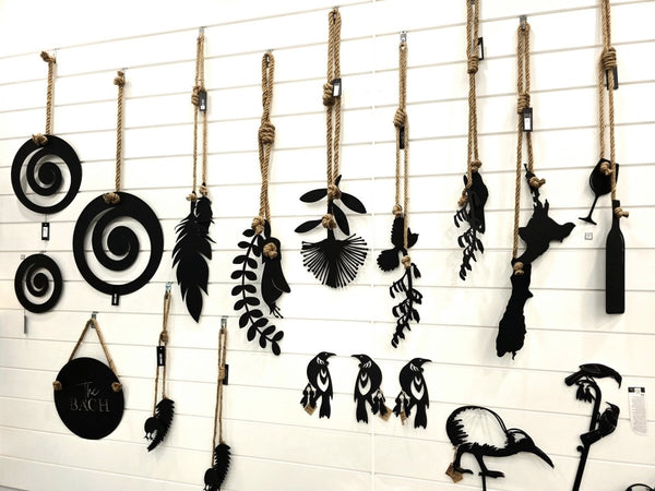 Collection of black decorative items hung on white slatwall with slatwall picture hooks in an art gallery