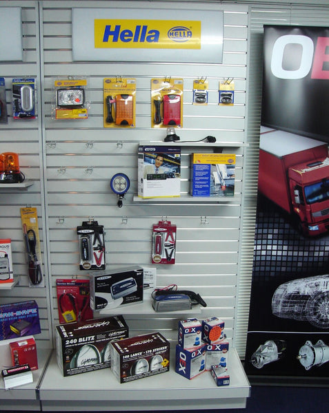 Header sign above a display of automotive parts and Hella branding in a store setting.