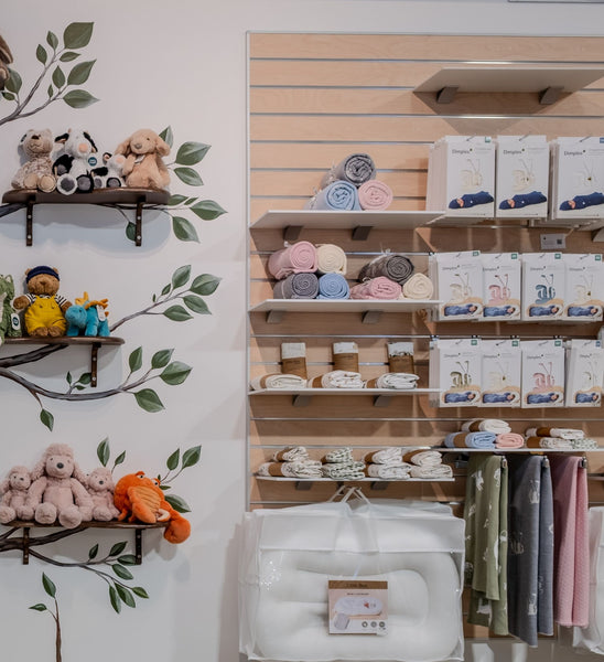 Baby product display on slatwall with shelves and wall decorations in a store.
