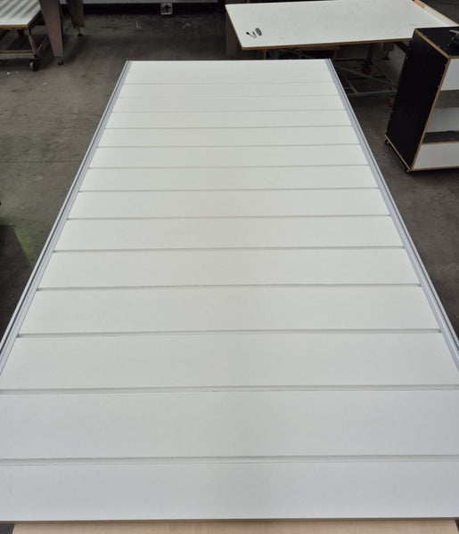 White PVJ inserts for slatwall panel with horizontal slats on a workshop floor create a clean, finished edge between panels. Durable and easy to install for retail wall displays, shopfitting and merchandising.