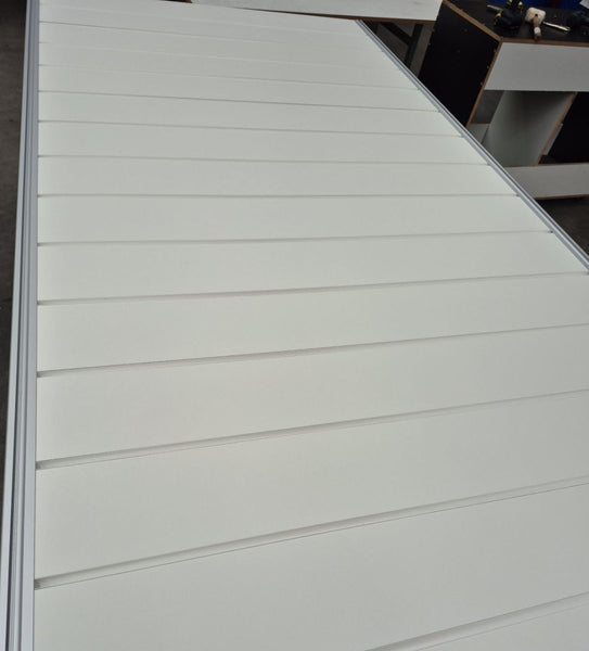 Close-up of a white panel with PVC J inserts for slatwall panels create a clean, finished edge between horizontal slats, likely part of a larger structure or product.