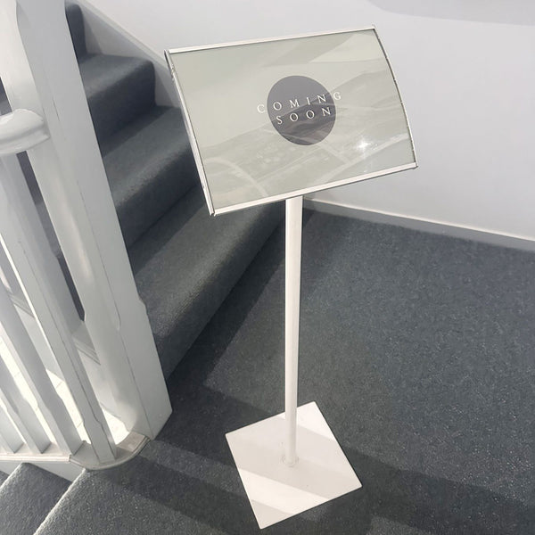 White horizontal radius postaframe sign stand with 'Coming Soon' sign on a staircase