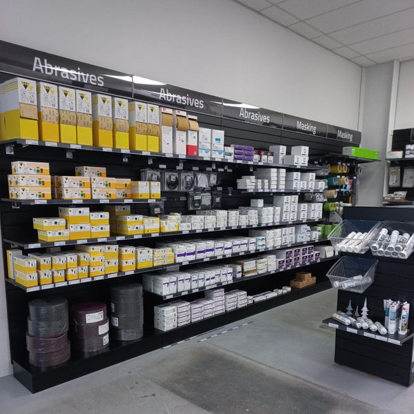 Header signage on shelving unit with various boxes labeled 'Abrasives' and 'Masking' in a store setting.