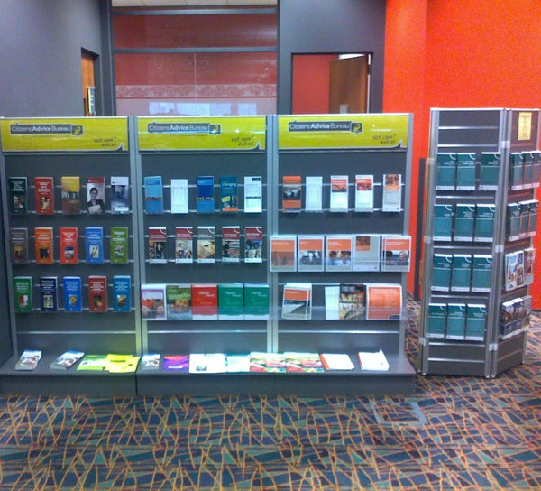 Radius header sign frames mounted above a slatwall shelving display system at the citizen advice bureau