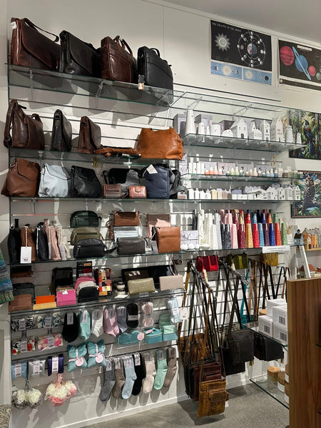 Display of handbags and accessories in a store with shelves and wall hangings.