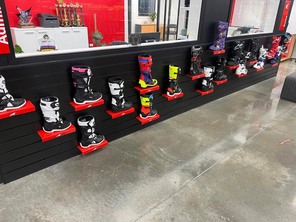 Plankwall clear acrylic shoe display shelves with motorboots on black slatwall in a retail setting