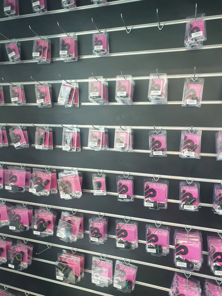 Merchandise in pink packets displayed on Plankwall light weight  single prongs on a black slatwall.