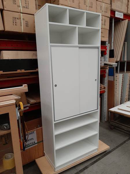 White storage cabinet with sliding door in a warehouse setting