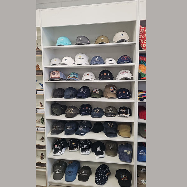 Shelf with various baseball caps displayed on white shelves.