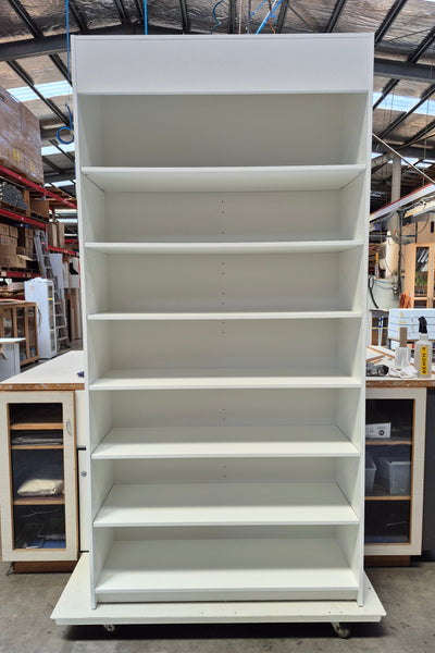 Large white display cabinet with shelves in a warehouse setting