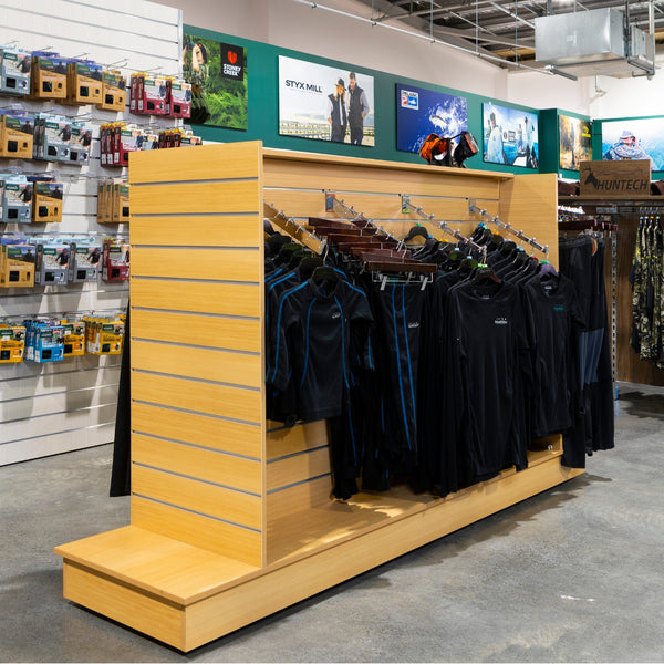 Side view of a Plankwall Retail Display Free-Standing Gondola in a rich wood finish with clothing apparel in a store setting