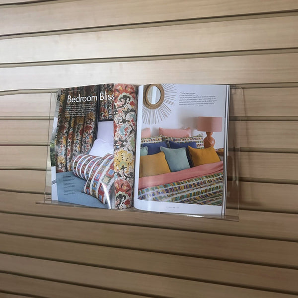 slatwall-mounted display shelf has an open magazine showing the feature editorial on linens 